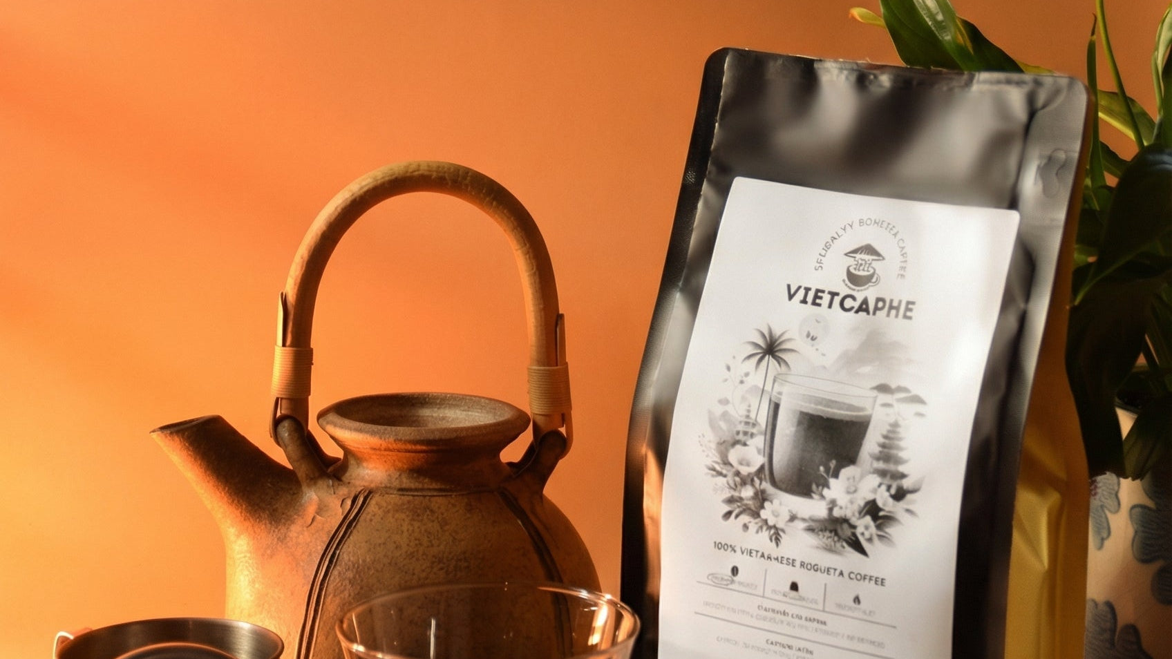Coffee bag labeled 'VIETCAPHE' next to a ceramic teapot, glass of iced coffee, and coffee filter on an orange background.